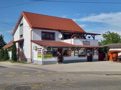 a white building with a red roof on a street at Kertész Vendégház in Hegykő