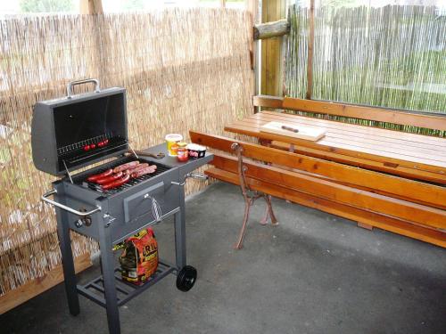 una parrilla de barbacoa con un banco en el fondo en Chatka Horec, en Stará Lesná