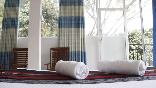 two towels sitting on a bed in front of a window at Boo Kirinda Holiday Resort in Badulla