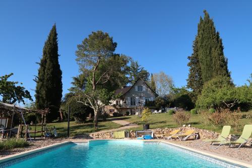 a pool with chairs and a house in the background at Chambres d'hôtes Le Verger in Prayssac