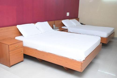 two beds in a room with white sheets and a table at Hotel Surya Residency Majestic in Bengaluru
