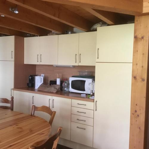 une cuisine avec des armoires blanches et un micro-ondes dans l'établissement Appartement typique,chaleureux et pratique, à Chamonix-Mont-Blanc