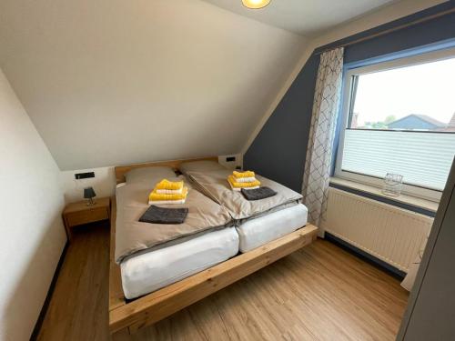 a small bed in a room with a window at Ferienhaus Kompass (ehemals Pension Hohlen) in Carolinensiel