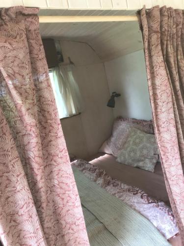 a bed with pink curtains in a bedroom at Leopold der Lamahütewagen in Oberndorf an der Melk