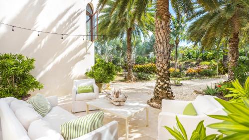a patio with white furniture and palm trees at Sandcastle Villa in Crocus Hill