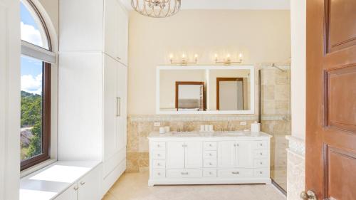 a white bathroom with a sink and a mirror at Sandcastle Villa in Crocus Hill