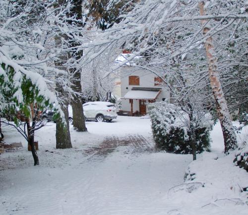 a snow covered yard with a car parked in front of a house at LA PONDEROSA Apart Hotel in San Carlos de Bariloche