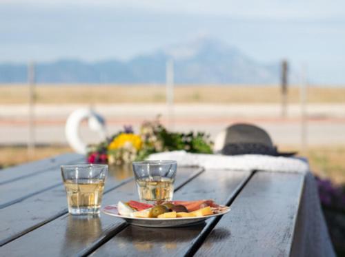 a table with a plate of food and two glasses on it at Malama Rooms in Sikia
