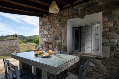 a stone house with a table and chairs on a patio at Malama Rooms in Sykia Chalkidikis