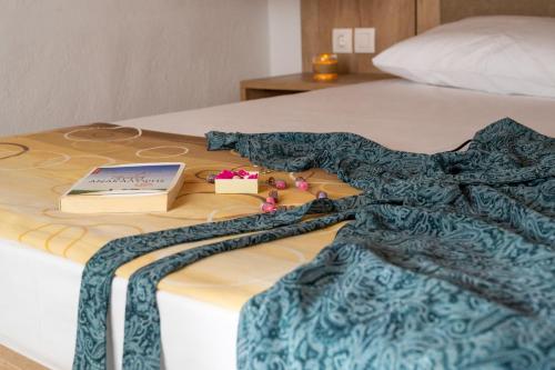 a bed with a blanket and a book on it at Malama Rooms in Sikia