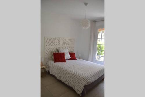 Un dormitorio con una cama con almohadas rojas y una ventana en Superbe T2 lumineux 3*** 10 mn à pied de la plage, en Le Pradet
