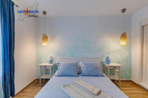 sypialnia z łóżkiem z niebieskimi ścianami i dwoma stołami w obiekcie Vivienda Vacacional Buganvillas w Costa Teguise