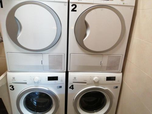 Duas máquinas de lavar roupa e uma máquina de lavar e secar roupa na casa de banho em Albergue Pension Porta Santa em Baleira