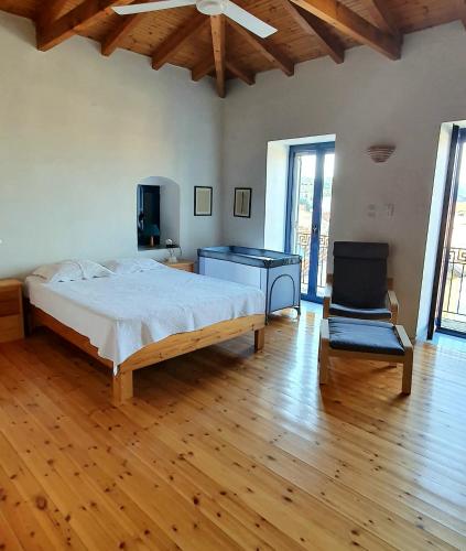 a bedroom with a large bed and a chair at Traditional Hillside Cottage in Gythio