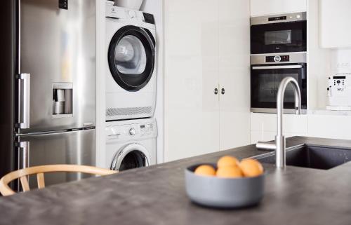 a kitchen with a counter with a washing machine and a bowl of oranges at Elaia Luxury Suites Mykonos in Mýkonos City