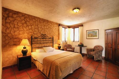 Habitación de hotel con 1 cama y 2 sillas en Villa Colonial en Antigua Guatemala