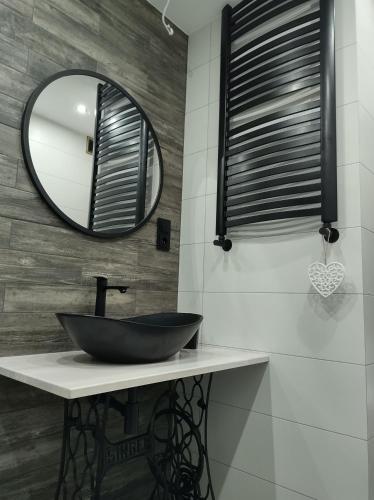 W łazience znajduje się czarna umywalka i lustro. w obiekcie Dom na skraju lasu w mieście Serwy