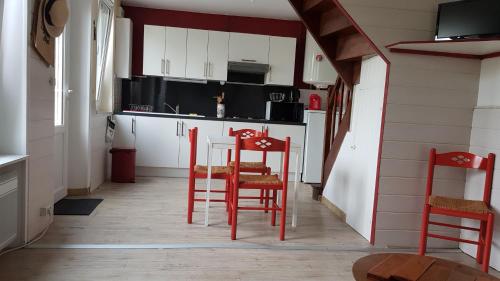 - une cuisine avec deux chaises rouges et une table dans l'établissement Petite maison mignonette, à Pléneuf-Val-André