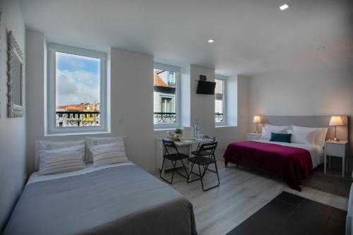 a bedroom with two beds and a table and two windows at Aveiro´s Dock Apartments in Aveiro