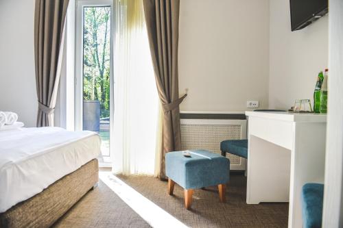 a bedroom with a bed and a chair and a window at Vila Savka in Vrnjačka Banja