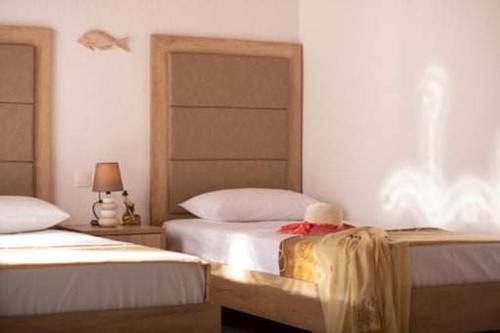 a bedroom with two beds and a lamp and a bedvisor at Malama Rooms in Sikia