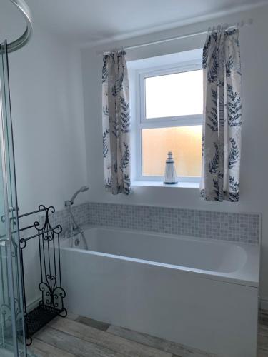 a white bath tub in a bathroom with a window at Driftwood House in Portaferry