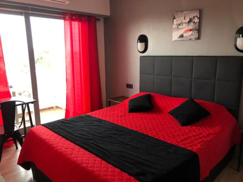 a bedroom with a red and black bed with red curtains at Hôtel Le Pescadou in Argelès-sur-Mer