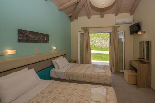 a hotel room with two beds and a window at Villas Porto Kamini Afionas Corfu in Afionas