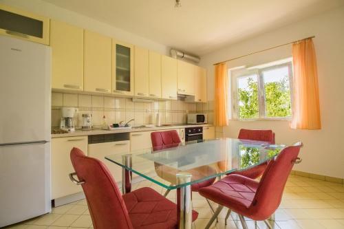 a kitchen with a glass table and red chairs at Apartments Joseph and Mary in Trogir
