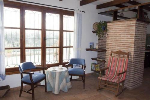 a living room with chairs and a table and windows at Huerta Solana in Castril