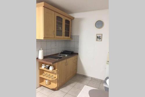 een kleine keuken met houten kasten en een wastafel bij JAndi apartman in Hévíz