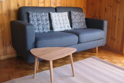 Alpia 26 - Zwei Zimmerwohnung in traditionellem Walliser Haus في Gasenried: أريكة زرقاء مع طاولة قهوة في غرفة المعيشة