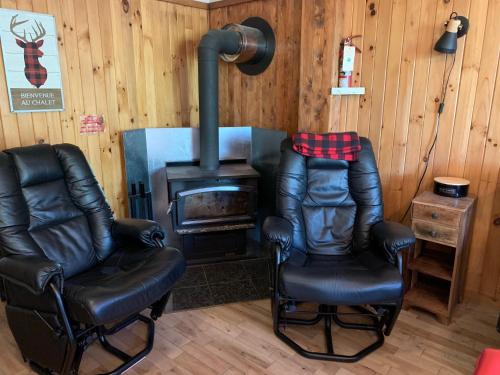 two leather chairs and a stove in a room at Aux Pignons Rouges Camping & Chalets in Saint Romain