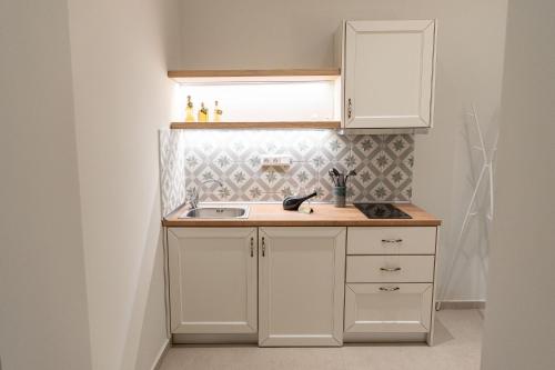 a kitchen with white cabinets and a sink at Mageiras Boutique Hotel in Afitos