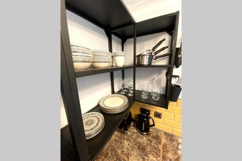 a shelf with plates and dishes in a kitchen at Spacious 2 Bed APT sleeps 4 near Bournemouth Beach in Bournemouth