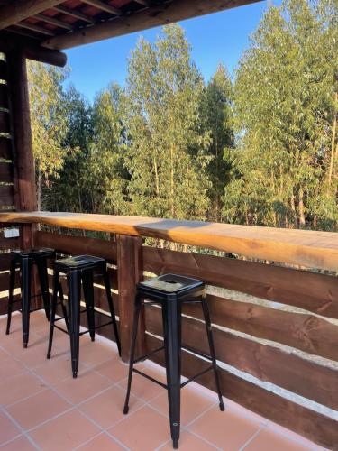 a bar on a deck with four stools at Monte da Rocha in Santiago do Cacém