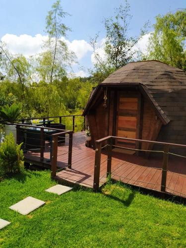 a wooden deck with a gazebo in the grass at Glamping Cantabria in Tunja