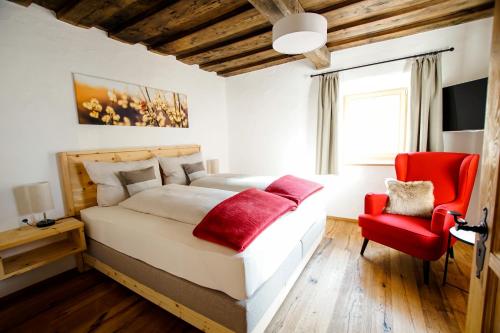 - une chambre avec un grand lit et une chaise rouge dans l'établissement Adelheid Keusche - DAS Chalet in Rennweg am Katschberg, à Rennweg