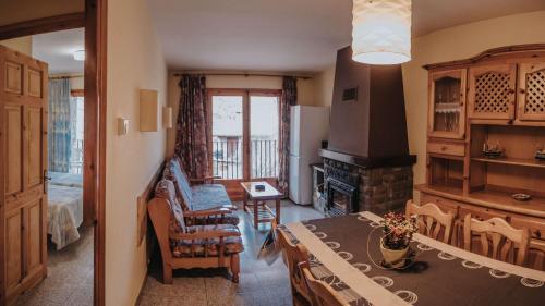 a living room with a dining table and a fireplace at Apartaments Castellar de n'Hug in Castellar de NʼHug