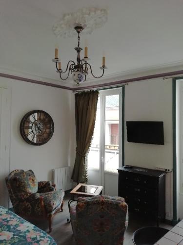 a living room with a chandelier and a tv and chairs at Le DINGSON in Arromanches-les-Bains