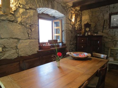 a wooden table in a stone room with a vase of flowers on it at Poolhouse Roc (3458) in Roč
