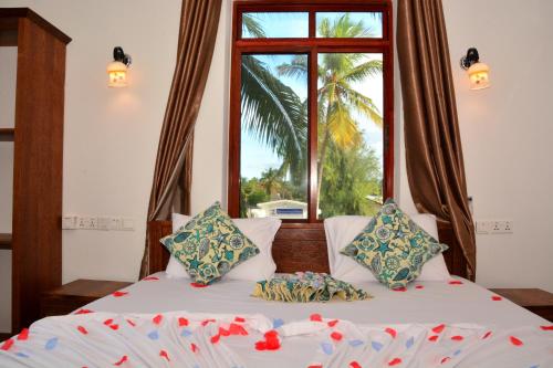 two beds in a room with a window at Zanoceanique Hotel in Matemwe