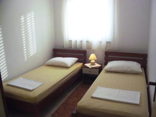 two beds in a small room with a window at House Vranjica (608) in Seget Vranjica