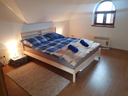 a bedroom with a bed with blue pillows and a window at Villa Kőrózsa Vendégház Tihany in Tihany