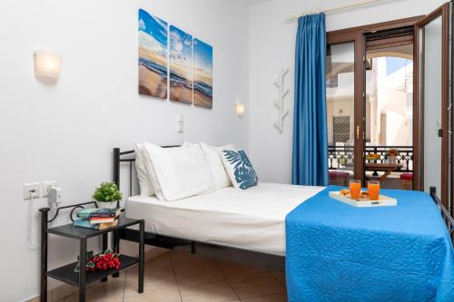 a bedroom with a bed with blue curtains and a table at NAXOS DIAMOND Studios Apartments in Naxos Chora
