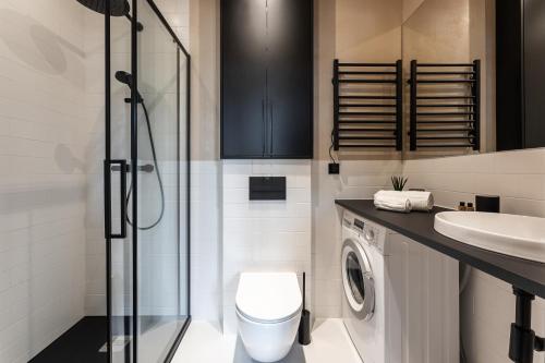 een badkamer met een toilet, een wastafel en een wasmachine bij Morning Light Sopot Apartment in Sopot