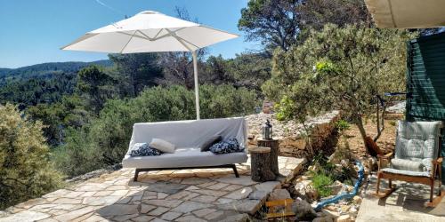 un sofá blanco sentado bajo una sombrilla en un patio en House on Punta, en Vela Luka