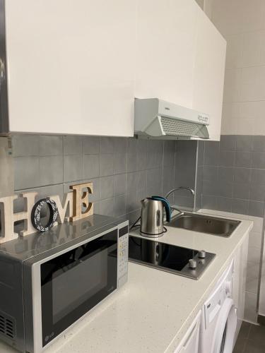 uma cozinha com um lavatório e um fogão forno superior em PLAYA, SOL Y CENTRO HISTORICO em Málaga