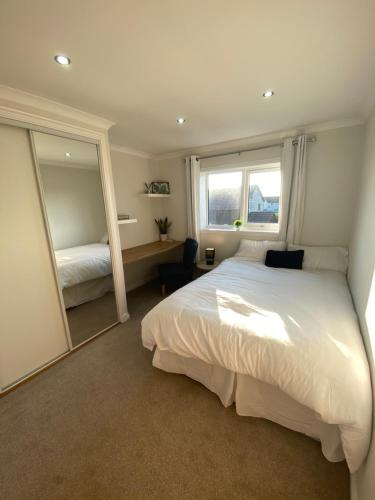 a bedroom with a large white bed and a mirror at Sigurd House in Thurso