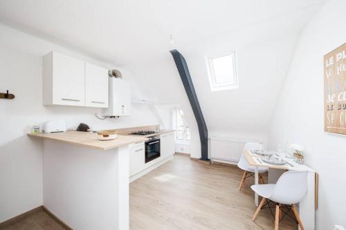 a kitchen with white cabinets and a table and chairs at Charmant T1 au cœur du centre historique de Dinan in Dinan